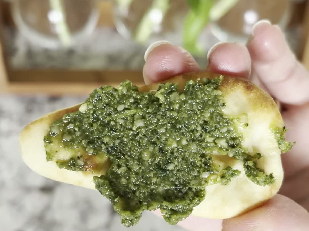 Cashew basil pesto spread across a piece of bread in a home kitchen.
